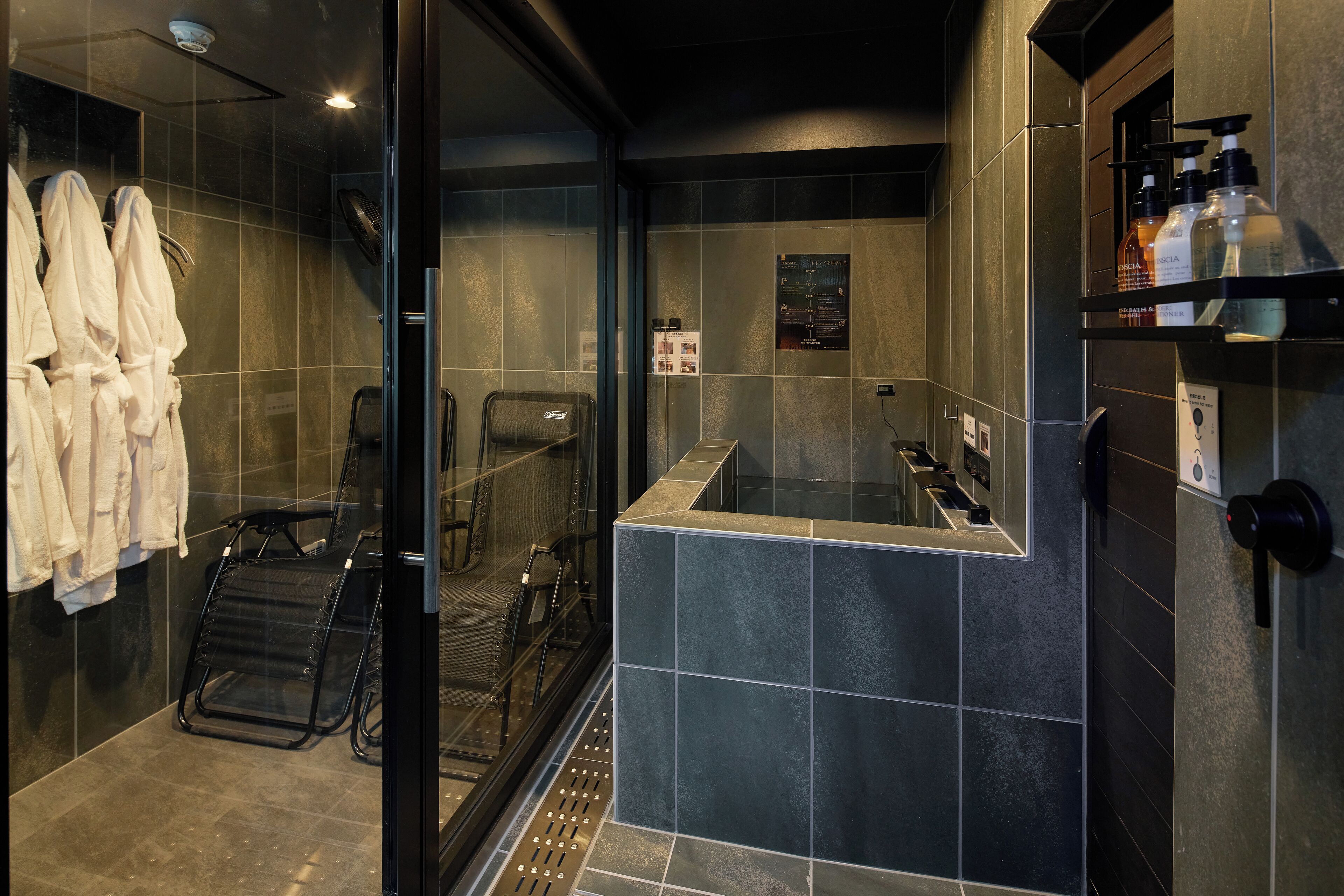 A modern bathroom with a glass shower enclosure, a built-in bench, and a shelf with toiletries.