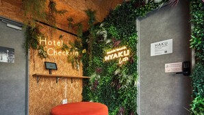 A hotel reception area with a wooden wall, a neon sign reading "Hotel Check-in", and a sign for "Haku Private Sauna". - B/C APARTMENT Asakusa Hanazono Dori Hotel with Rental Car and Sauna (Tokyo)