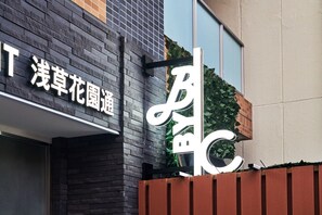 A building facade with a large, white, stylized 'B' sign and a smaller sign with Chinese characters. - B/C APARTMENT Asakusa Hanazono Dori Hotel with Rental Car and Sauna (Taito-ku)