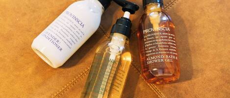 Three bottles of Provinscia shower gel on a brown leather surface.