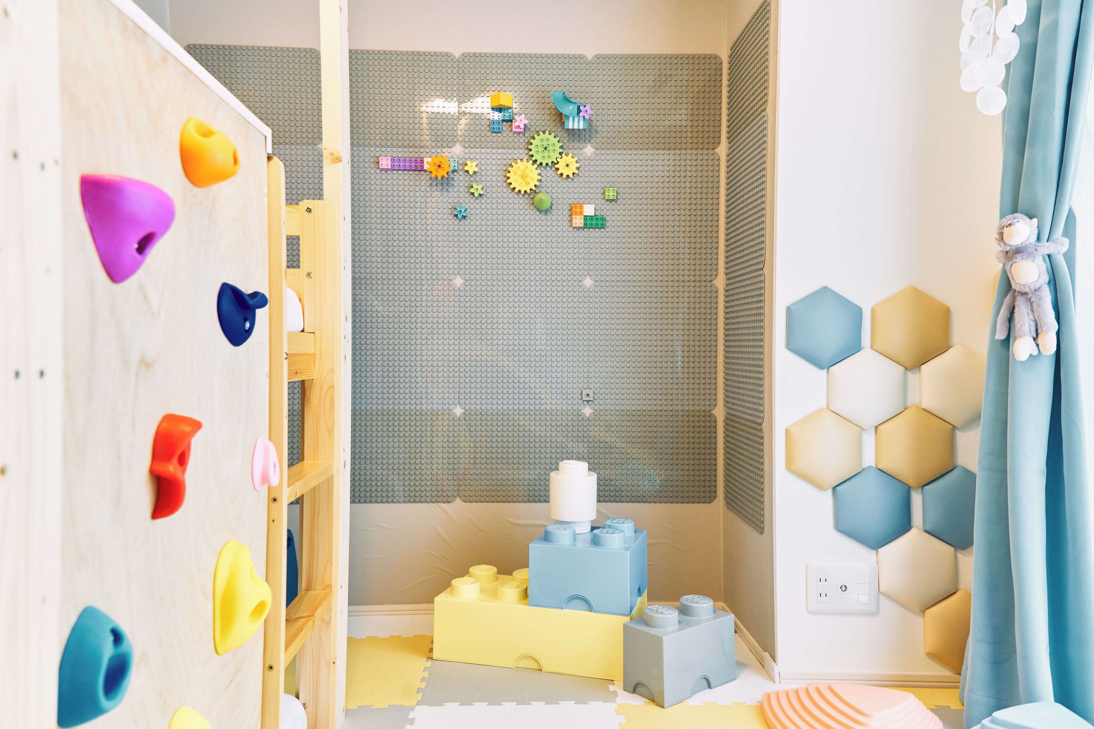 Un cuarto de juegos infantil con una pared de escalada, juguetes coloridos y un adorno mural hexagonal.