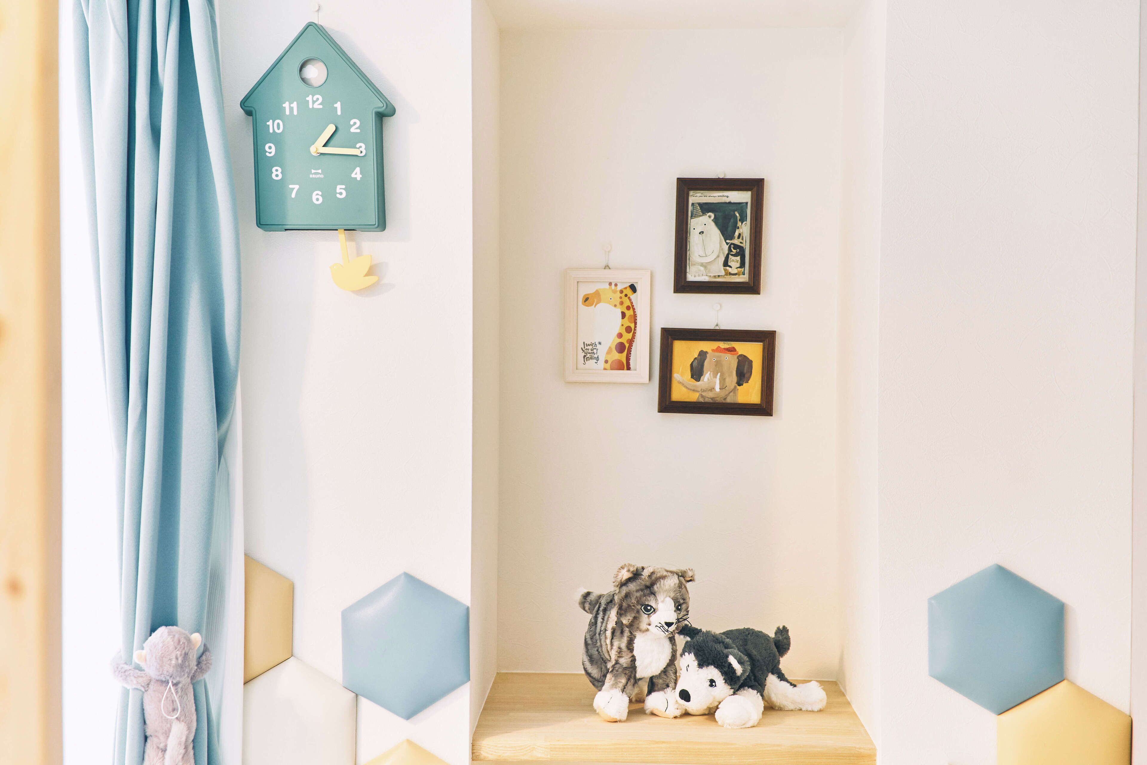 A room with a blue curtain, a wall clock, and two framed pictures.