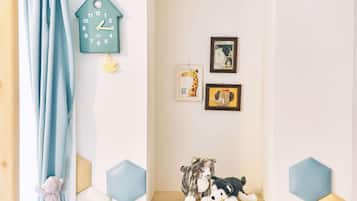 A room with a blue curtain, a wall clock, and two framed pictures.