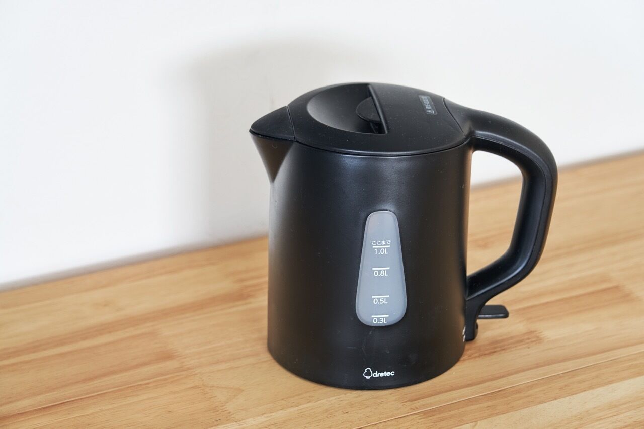 A black electric kettle with measurement markings on the side, placed on a wooden surface.