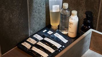 A bathroom counter with various toiletries including a bottle of gel cleansing, a bottle of moisturizing milk, and several hair care products.