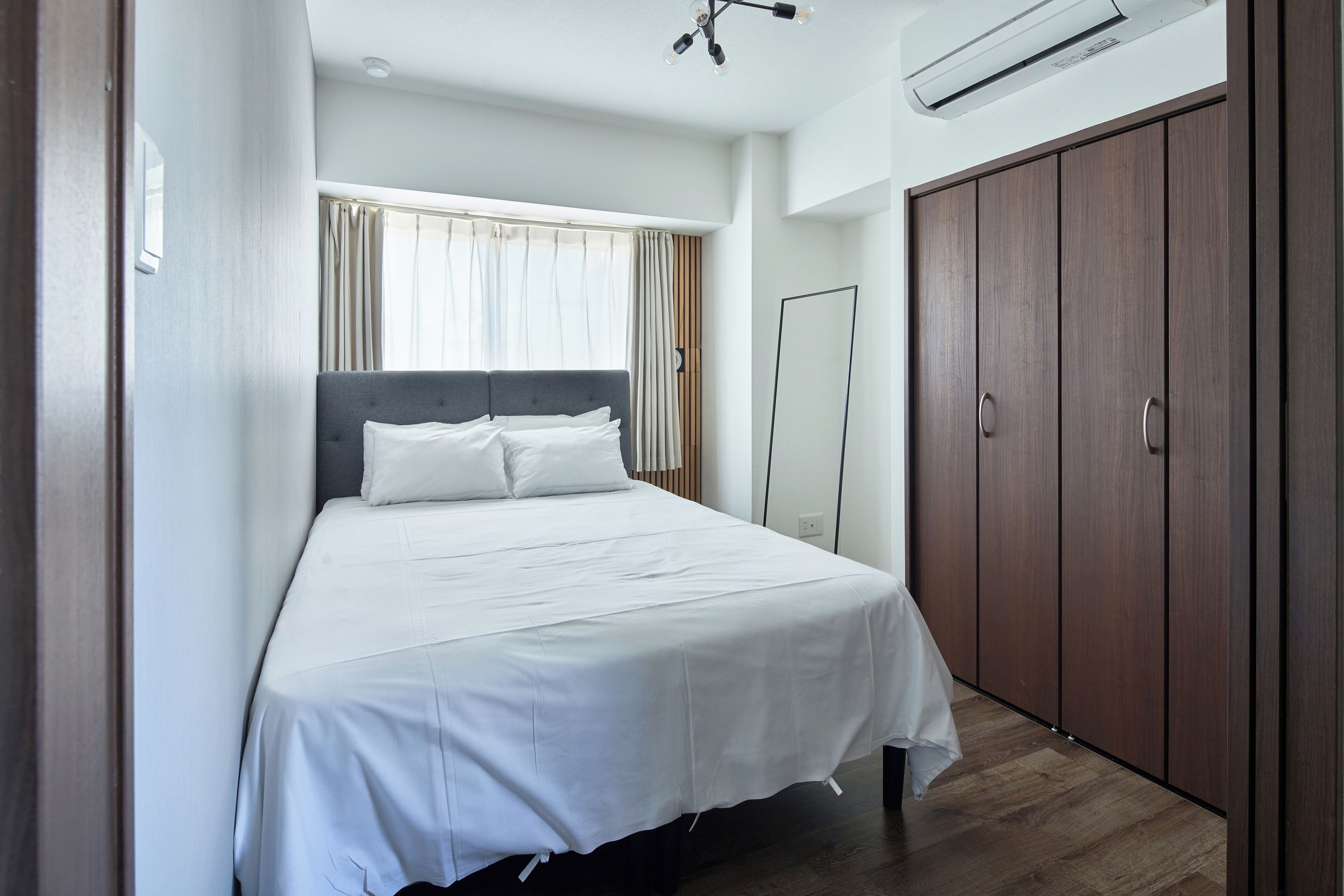 A bedroom with a bed, a wardrobe, and a mirror.