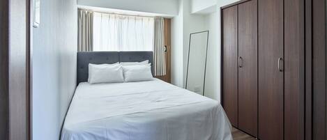 A bedroom with a bed, a wardrobe, and a mirror.