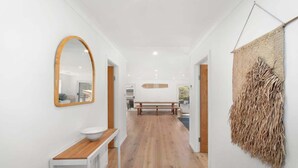 A hallway with a wooden bench, a white sink, and a mirror.