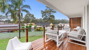 A balcony with outdoor furniture, a view of the neighborhood, and a wooden deck.