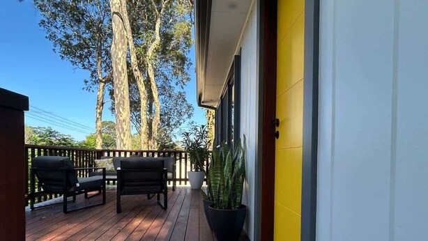 A wooden deck with two black chairs and a potted plant. - Coastal Chillout at Mossy (Mossy Point)