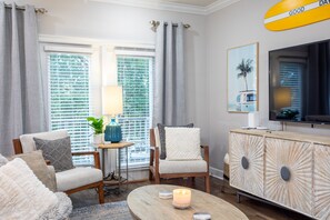 Relax in this stylish living room with a comfortable seating area, wooden coffee table, and large flat-screen TV.