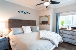 Relax in this inviting bedroom with a large bed, ceiling fan, and wall-mounted mirror.
