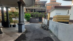 A narrow alleyway with a concrete floor, surrounded by buildings and potted plants. - OYO Life 93160 Kost Jenny Karawang (Karawang)