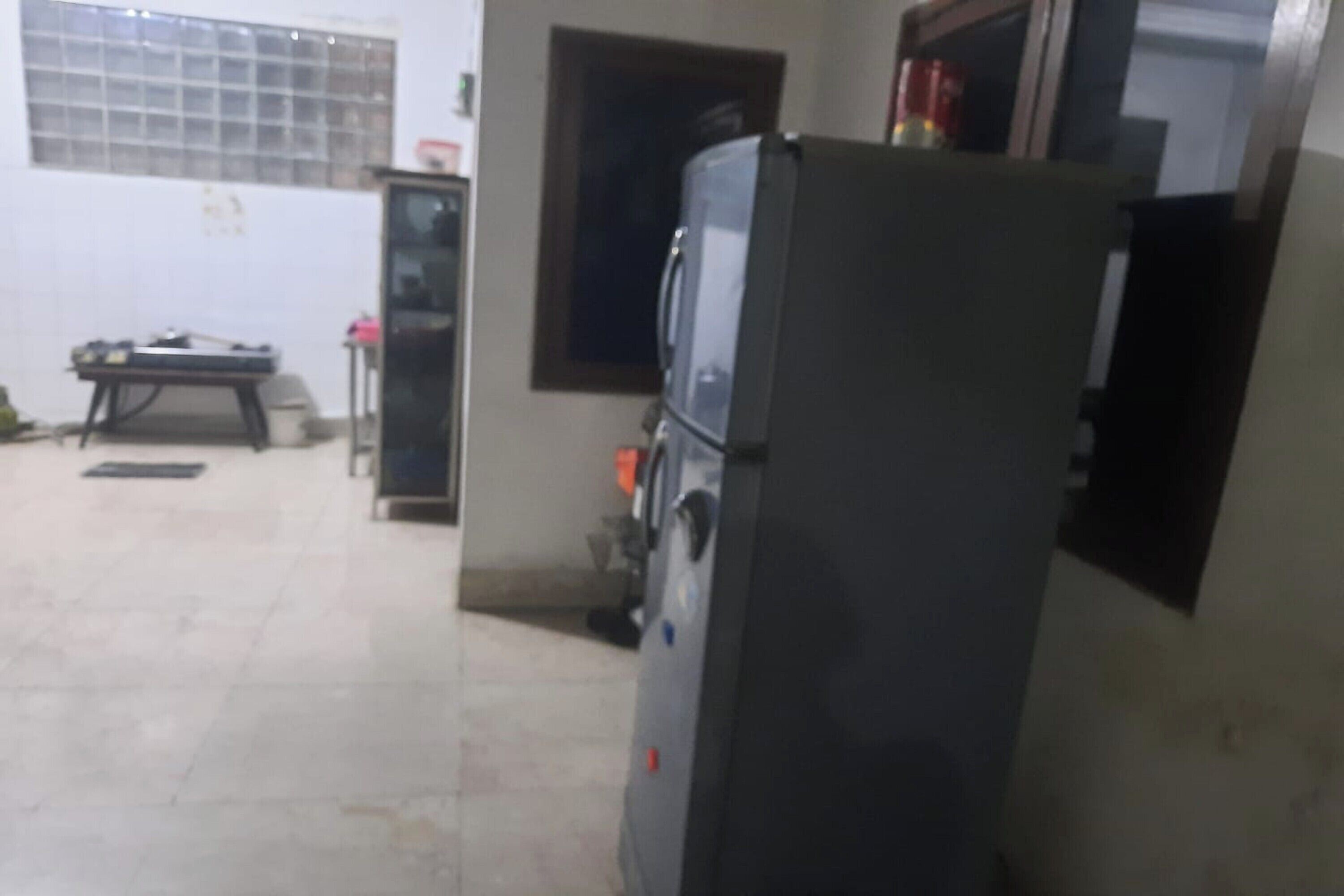 Una cocina con refrigerador, una mesa y un ventanal.