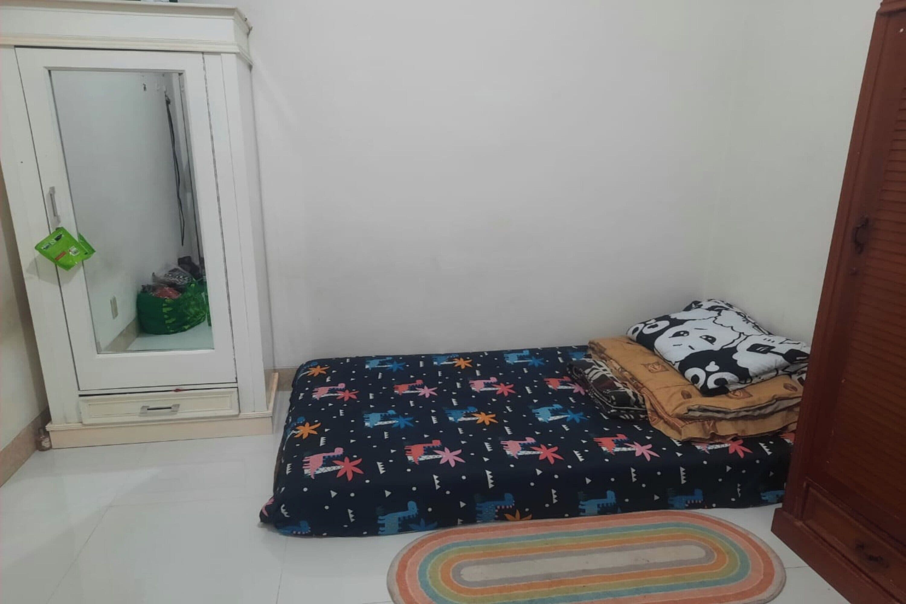 Una habitación pequeña con cama, armario y espejo.