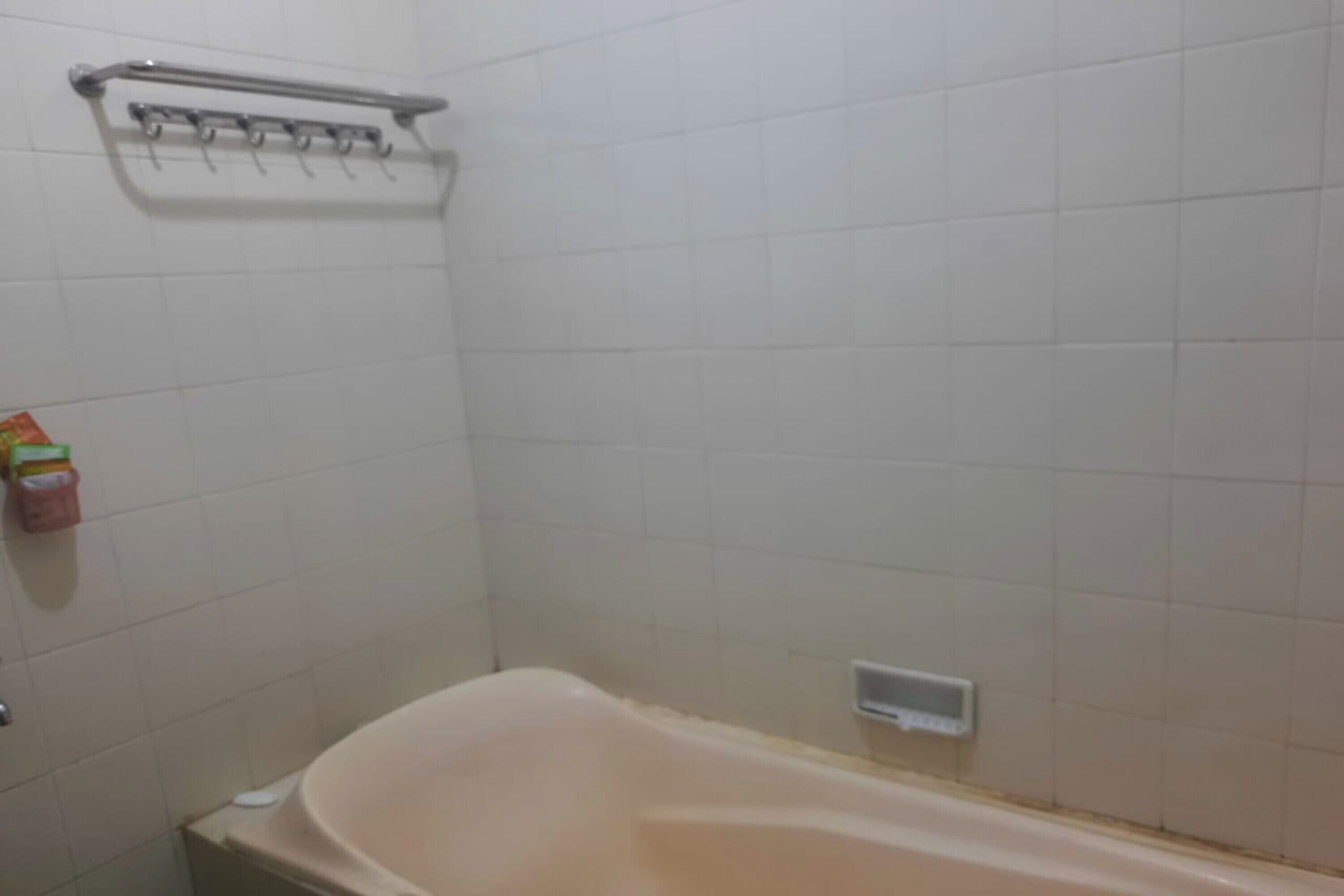 Un bagno con una vasca, un portasciugamani e un dispenser per sapone.