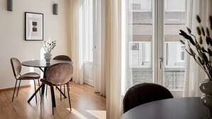 A dining area with a round table, four chairs, and a vase with dried plants. - ATH121 - Elysian 2BR Apartment in Plaka 1 (Athina)