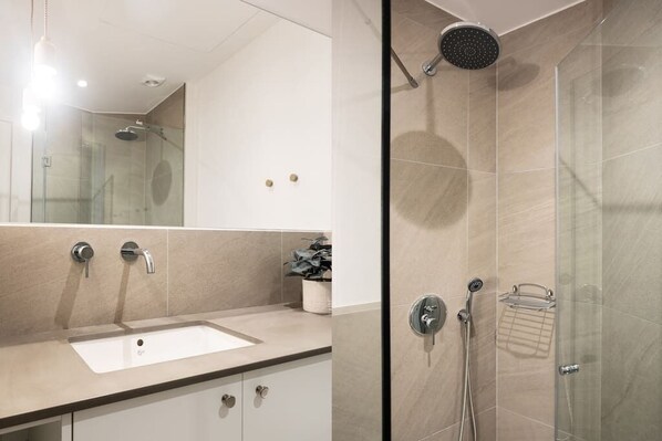 A modern bathroom with a glass-enclosed shower, a sink, and a mirror.