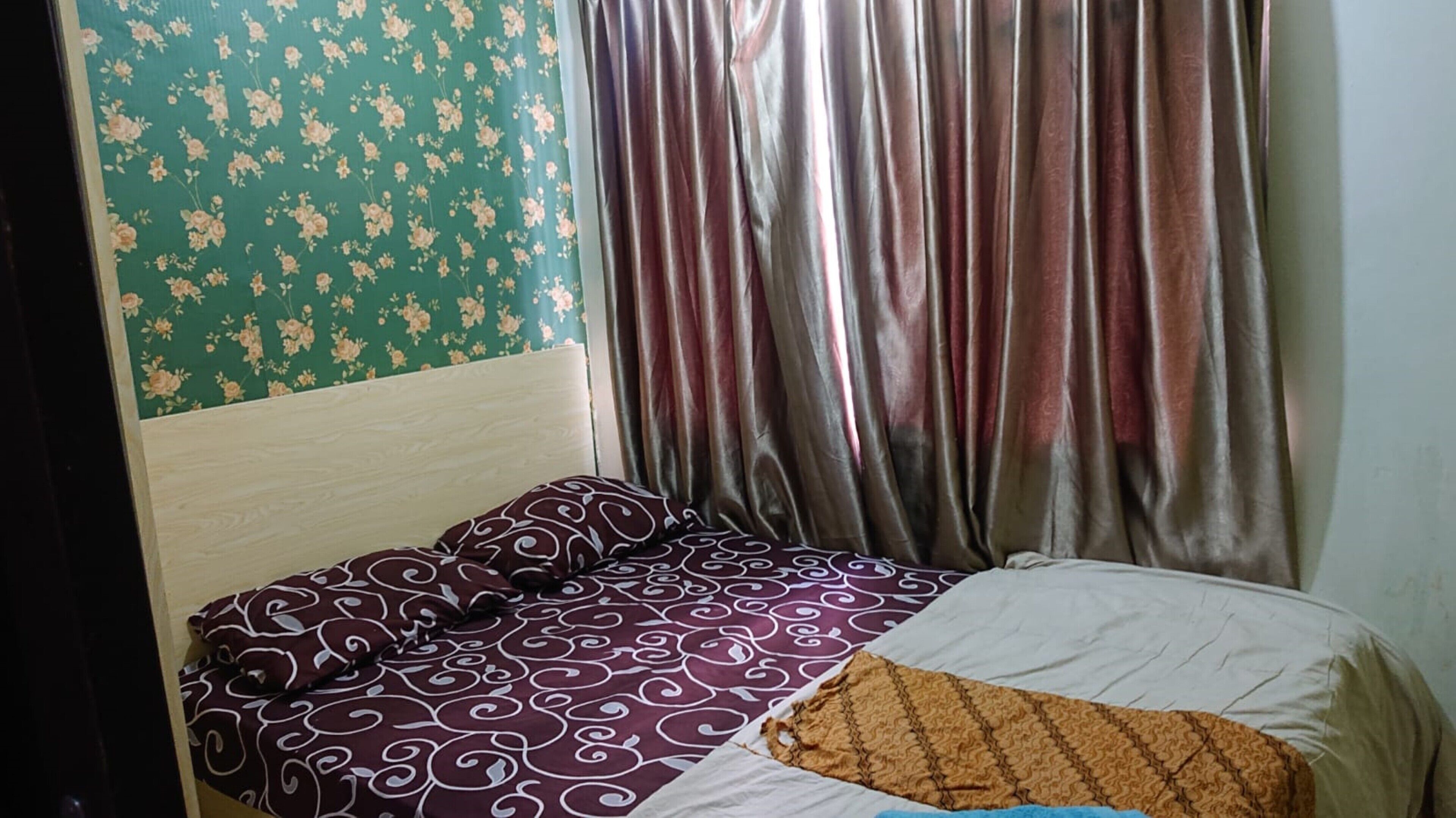 Una cama con ropa de cama estampada, un cabecero de madera y una pared cubierta de papel tapiz floral.