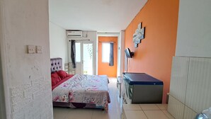 A bedroom with a bed, a dresser, and an air conditioning unit. - OYO Life 93139 Apartemen Grand Sentraland By Evi (Karawang)