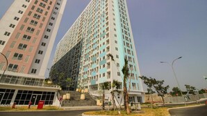 A high-rise residential building with multiple floors, a central staircase, and a gated entrance. - OYO Life 93139 Apartemen Grand Sentraland By Evi (Karawang)