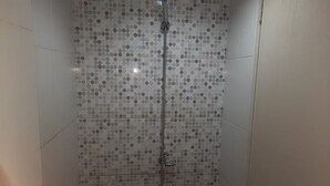 A shower with a polka dot tile pattern and a handheld showerhead. - OYO Life 93139 Apartemen Grand Sentraland By Evi (Karawang)