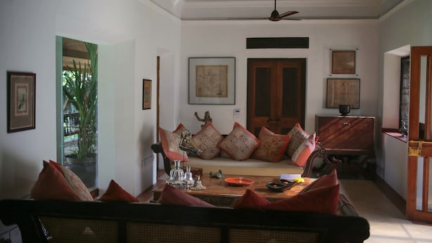 A living room with a sofa, a dining table, and a ceiling fan.