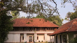 A traditional building with a tiled roof, a balcony, and a well-maintained garden. - Chittoor Kottaram - CGH Earth (Kanayannur)