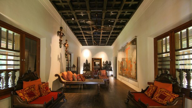 A room with a wooden floor, a large bed with red bedding, and a ceiling fan. - Chittoor Kottaram - CGH Earth (Kanayannur)