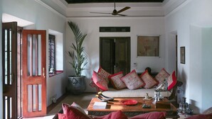 A traditional living room with a sofa set, decorative pillows, a wooden coffee table, and a ceiling fan. - Chittoor Kottaram - CGH Earth (Kanayannur)