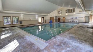 Una piscina interior con agua cristalina, suelo de baldosas y techo alto.
