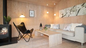 A cozy living room with a wooden interior, a sofa, a coffee table, a chair, a fireplace, and wall art. - "Fasti" - 300m from the sea by Interhome (Gilleleje)