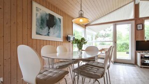 A dining area with a round table and four chairs, a hanging light fixture, and a large abstract painting on the wall. - "Fasti" - 300m from the sea by Interhome (Gilleleje)