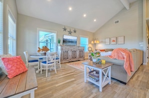 A spacious living room with a dining area, a sofa, and a TV.