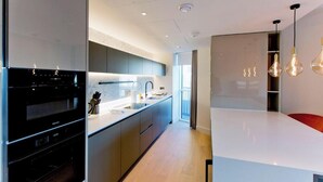 A modern kitchen with a built-in oven, a large island, and pendant lighting. - Modern Urban Retreat in Vibrant West London (London)