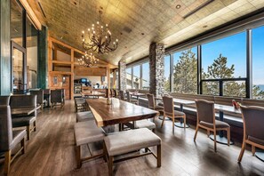 Un vaste espace dédié à la salle à manger, avec une longue table en bois, des bancs rembourrés et un lustre.