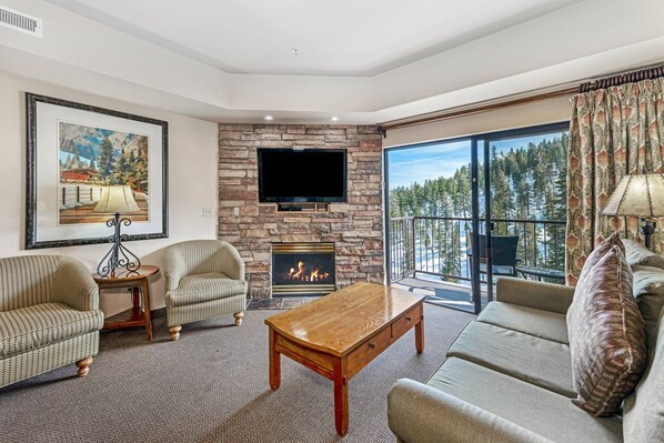 A living room with a stone fireplace, a flat-screen TV, and a sofa.