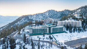 Ein großes Hotelkomplex mit mehreren Gebäuden, umgeben von schneebedeckten Bergen und Bäumen.