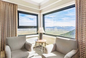 Enjoy expansive mountain views from the comfort of this cozy corner room, featuring a pair of plush armchairs and a small table.