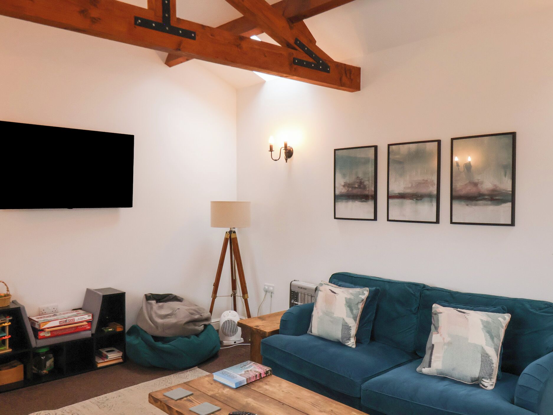 Un saló amb un sofà blau, una taula de centre de fusta, una làmpada de peu i un televisor de pantalla plana penjat a la paret.