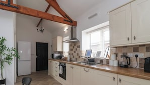 A modern kitchen with white cabinets, a wooden countertop, and a herringbone floor pattern. - Puffin (Bridlington)