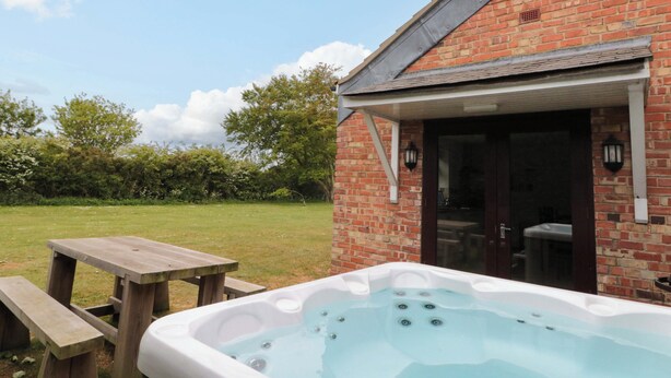 A brick building with a hot tub and a picnic table outside. - Kittiwake (Bridlington)