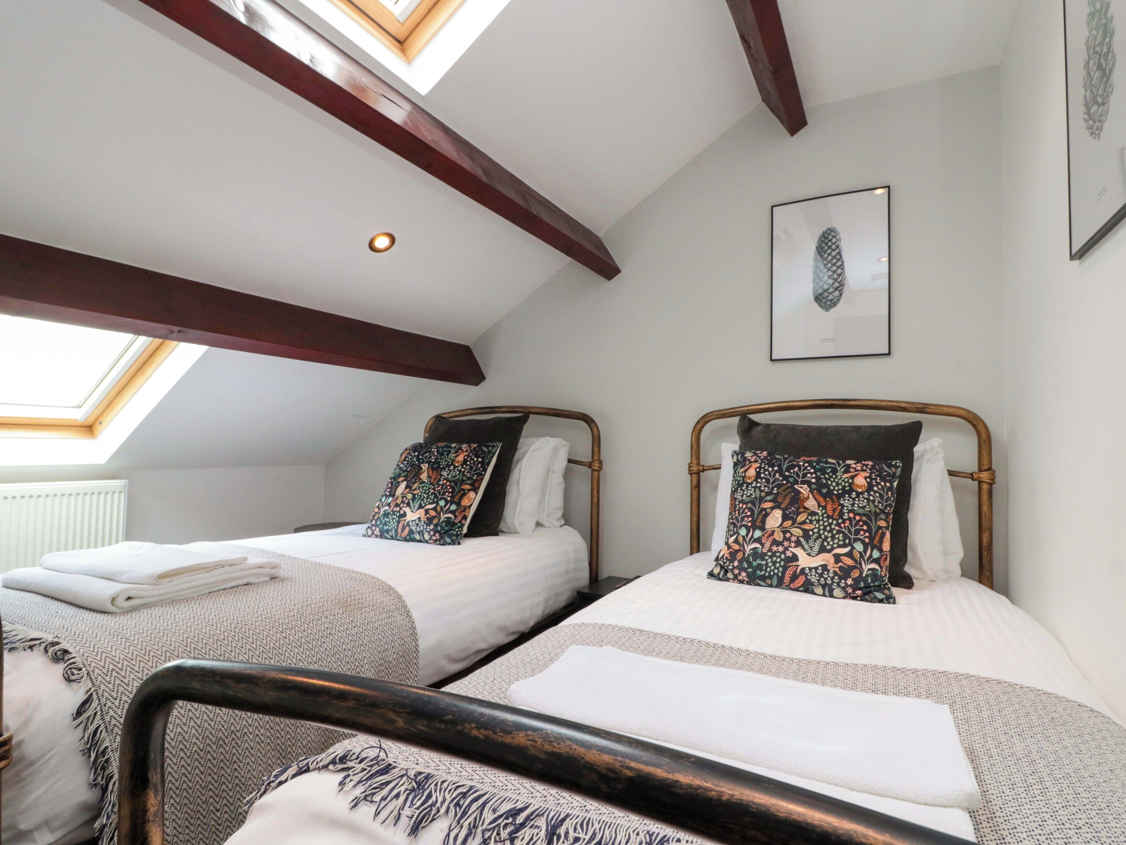 A bedroom with two beds, a skylight, and a framed picture on the wall.