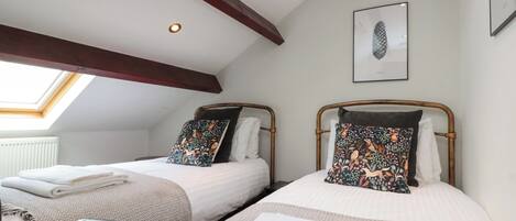A bedroom with two beds, a skylight, and a framed picture on the wall.
