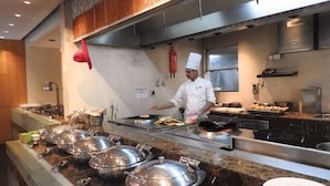 Un buffet avec plusieurs points de service, un chef qui prépare les plats et une variété de mets présentés sur le comptoir.