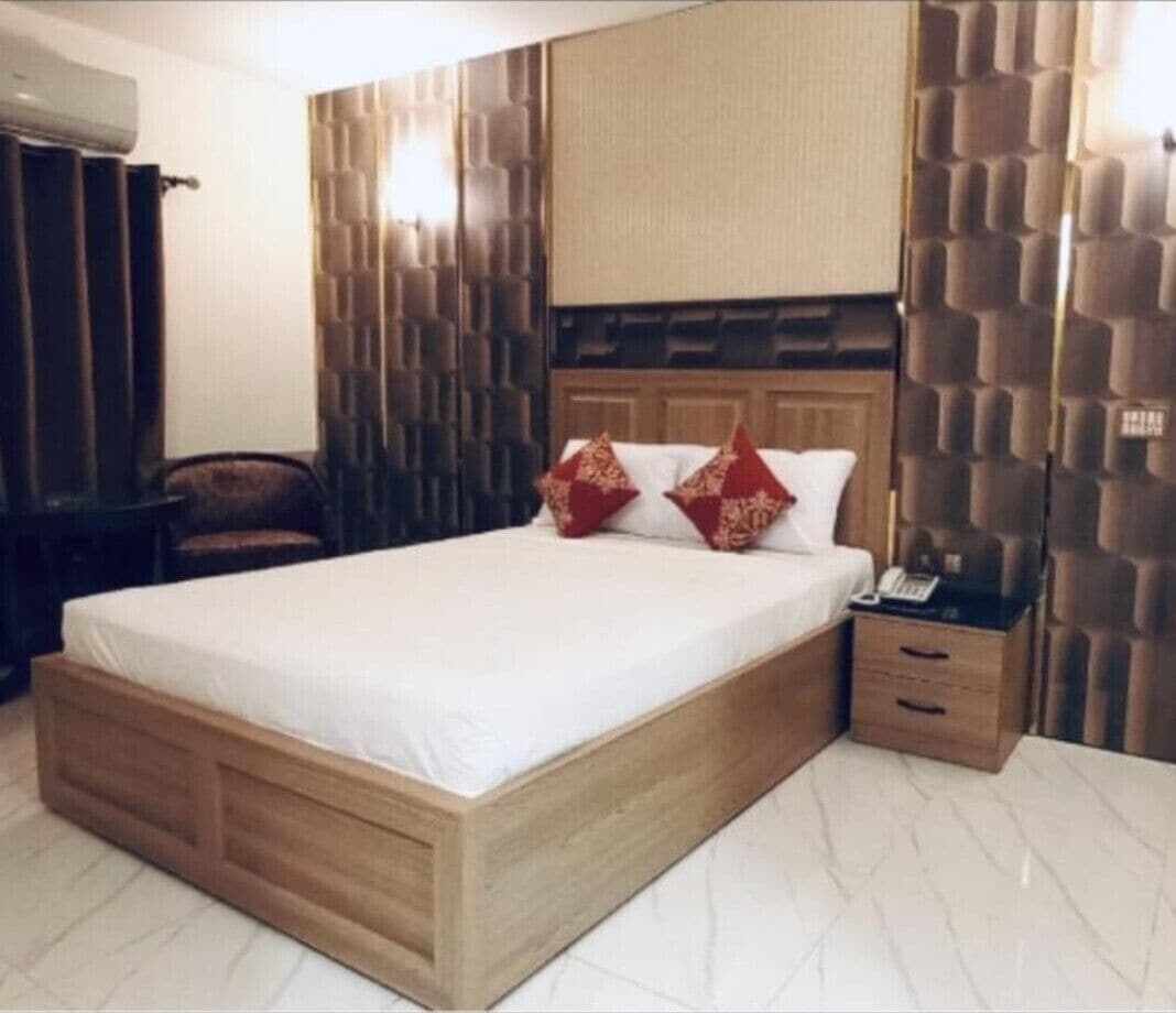 Una camera da letto con un letto in legno, un comodino, una sedia e un condizionatore d'aria a parete.