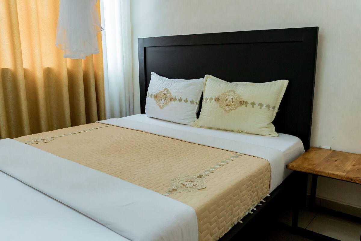 Una cama bien hecha con un edredón acolchado y dos almohadas con diseños decorativos.