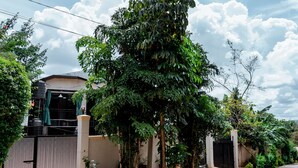 Un quartier résidentiel comprenant une maison, une entrée sécurisée et une végétation luxuriante.