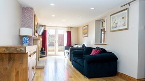 Un salon moderne avec un canapé bleu foncé, un plancher en bois et un meuble en bois sur lequel est posée une lampe.