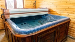 Une cabane en bois avec un jacuzzi au centre.